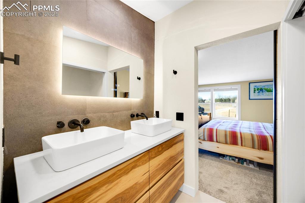 Image 21 of 49: Bathroom with double vanity, connected bathroom, and light carpet