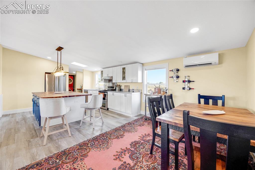 Image 9 of 49: Dining room featuring light wood-style flooring, an AC wall unit, a skyligh