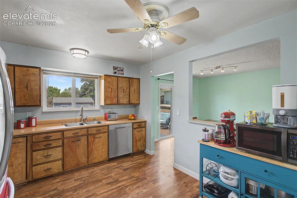 Image 10 of 30: Kitchen featuring wood-finish flooring, natural wood cabinetry, a double ba