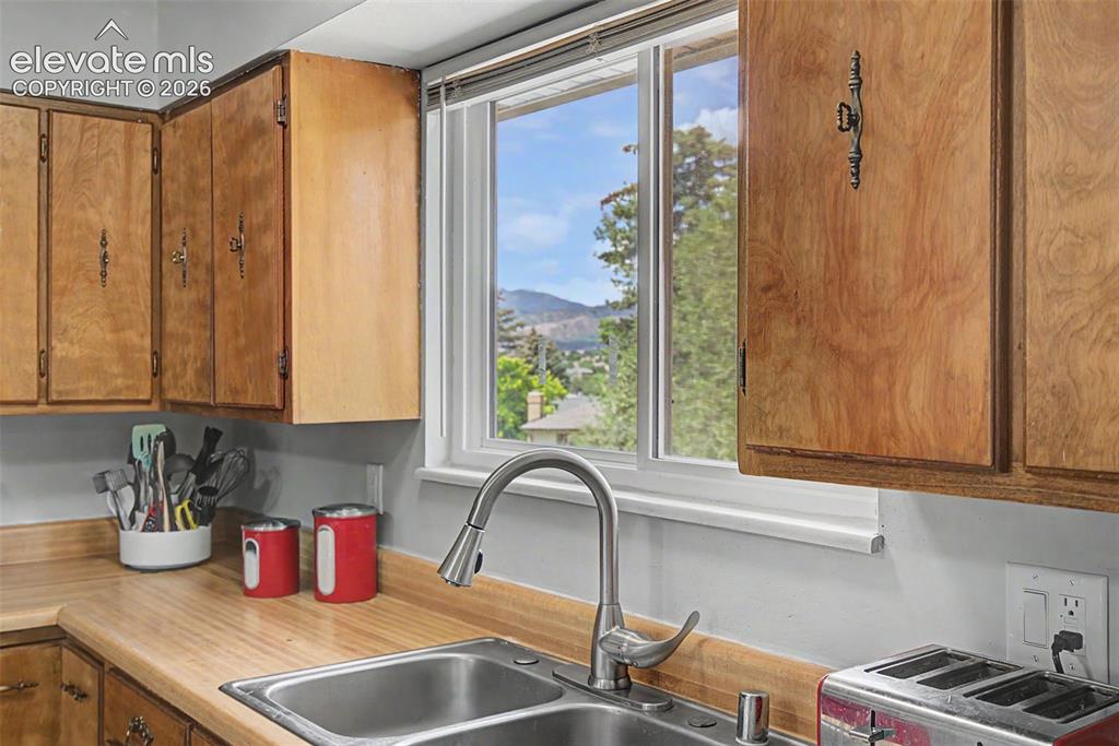 Image 13 of 30: Kitchen featuring wood cabinetry, a stainless steel double basin sink with