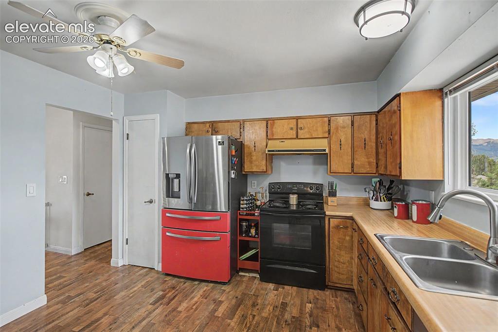 Image 14 of 30: Kitchen featuring wood-finish flooring, wood cabinetry, stainless steel sin