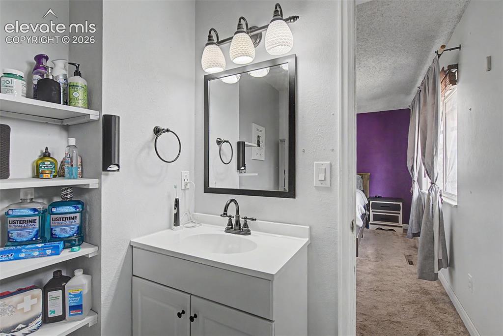 Image 18 of 30: Bathroom vanity with a rectangular sink, matte black faucet, and coordinati