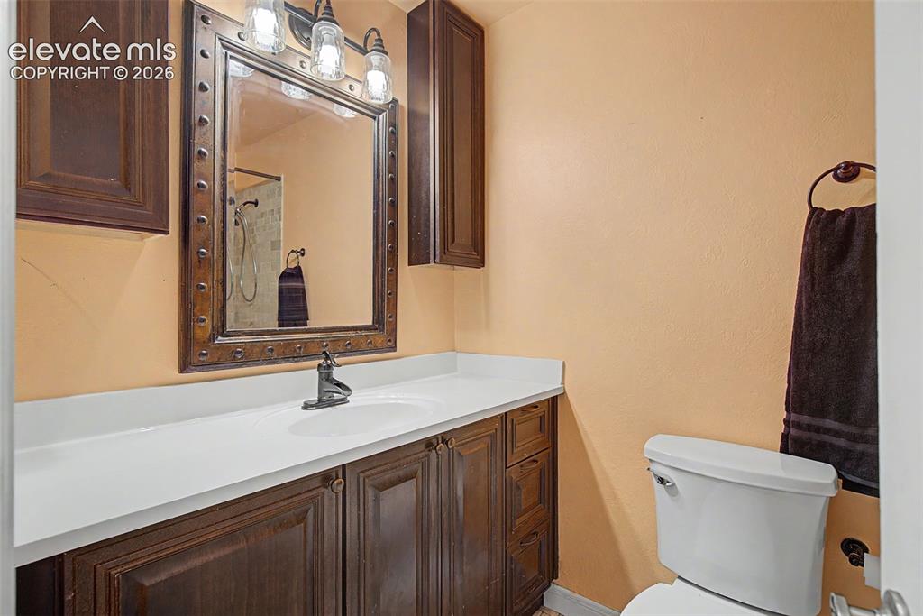 Image 20 of 30: Bathroom vanity with dark wood-finish cabinetry, a white countertop, and an