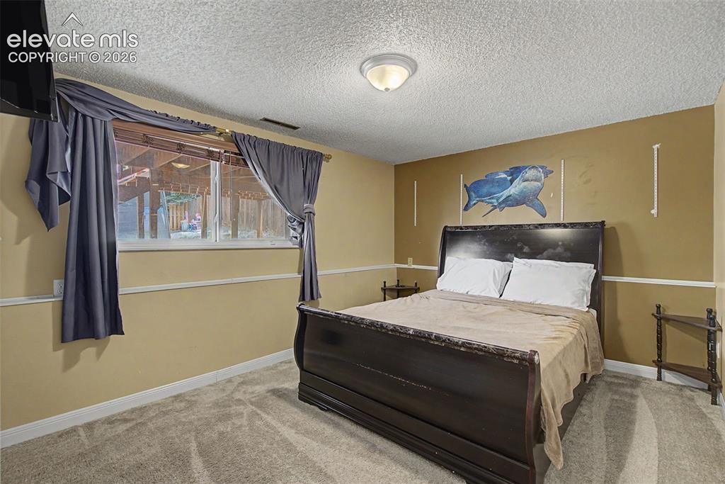 Image 25 of 30: Carpeted room featuring a window with a valance, light tan walls with white