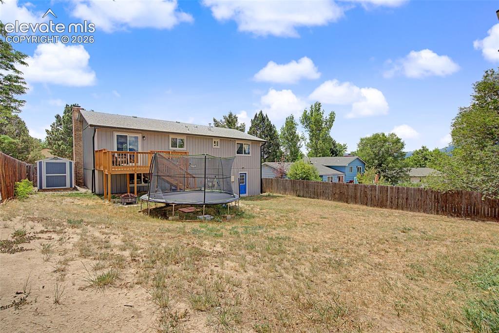Image 30 of 30: Rear exterior featuring a wood deck, sliding glass door, and a detached sto