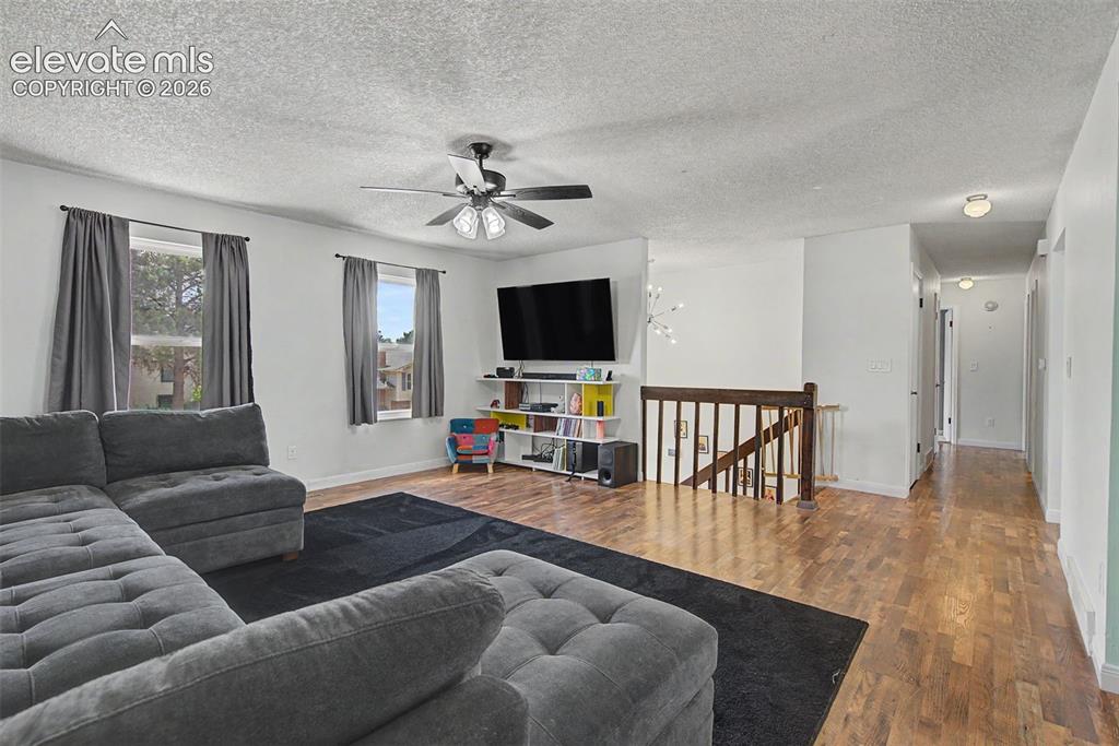 Image 5 of 30: Spacious living area featuring wood-finish flooring and a ceiling fan