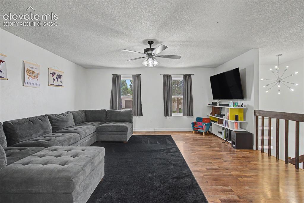 Image 6 of 30: Open-concept living area featuring wood-finish flooring, white walls, and a