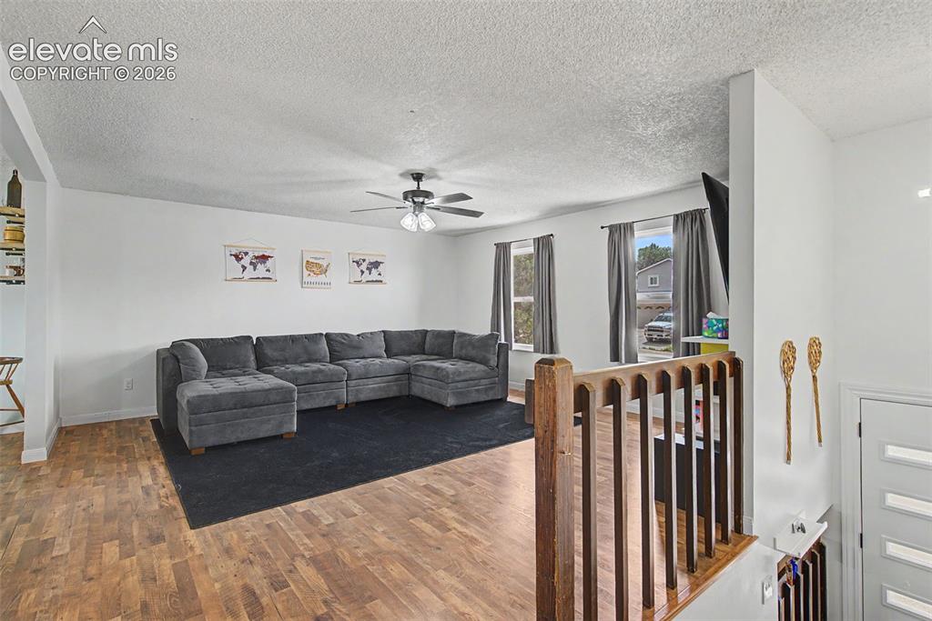 Image 7 of 30: Open-concept living area with wood-finish flooring, white walls, and a ceil