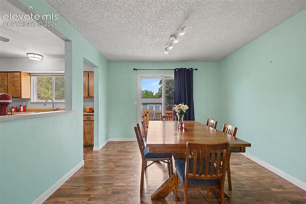 Image 9 of 30: Dining area featuring wood-finish flooring, a sliding glass door, and track