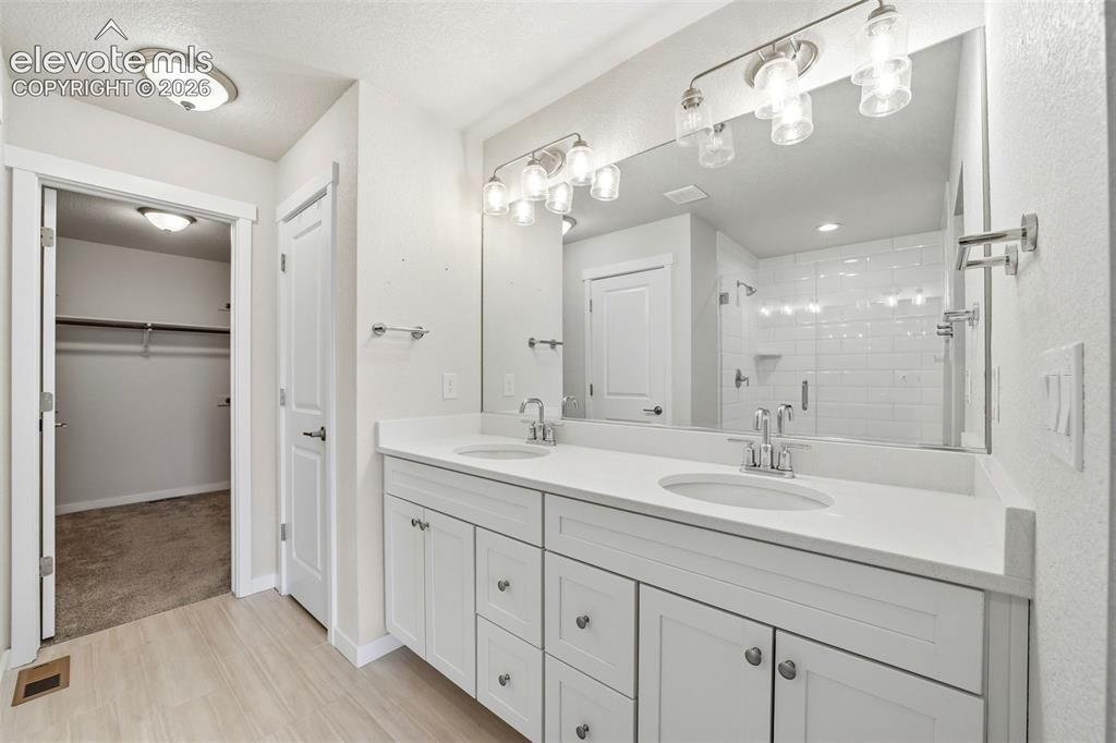 Image 21 of 23: Double vanity with white cabinetry, light-toned countertops, and brushed ni