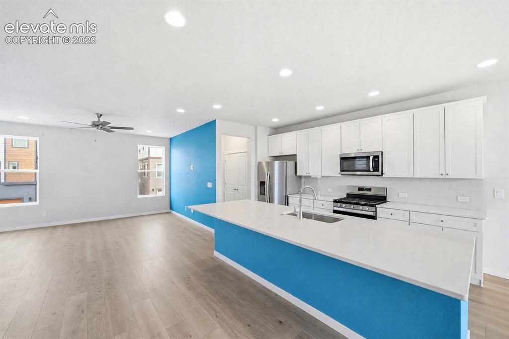Image 8 of 23: Kitchen island with a white countertop and integrated sink, stainless steel