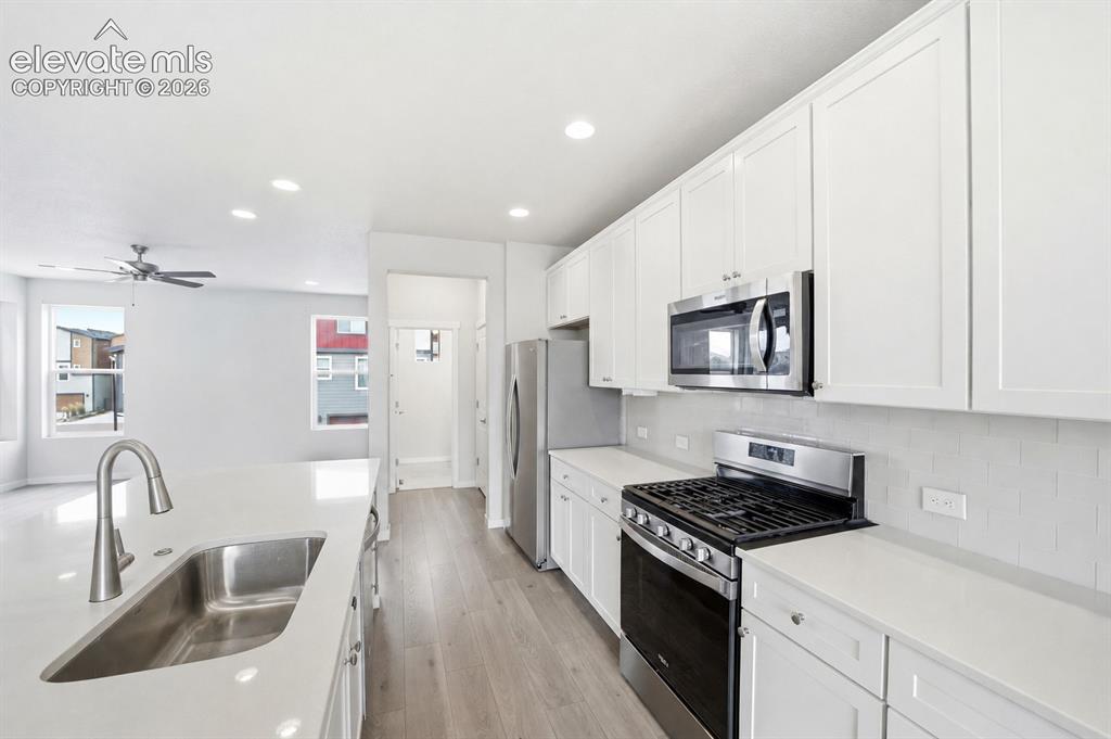 Image 9 of 23: Kitchen featuring white cabinetry, stainless steel appliances, a double bas