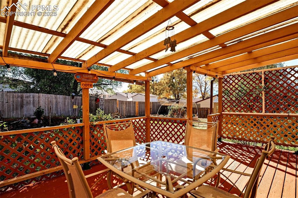 Image 26 of 36: Head out back to your very own covered wood deck with a corrgated roof that