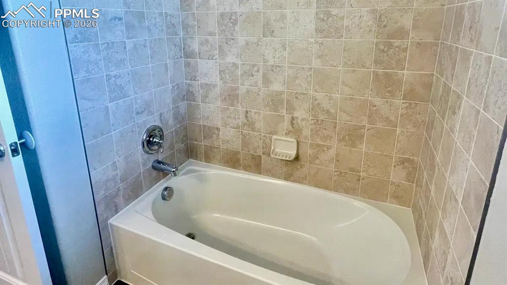 Image 12 of 15: Upper-level full bath with tiled surround