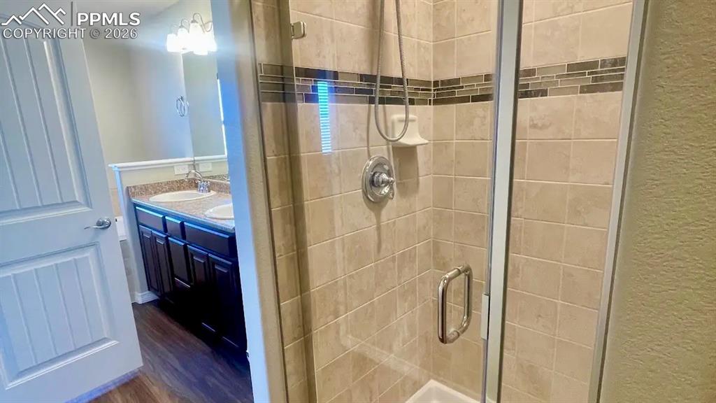 Image 7 of 15: Primary bathroom with tiled walk-in shower and dual-sink vanity
