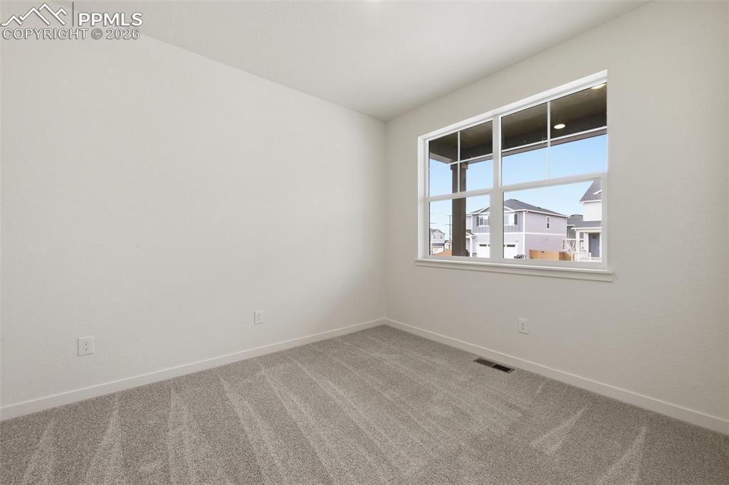 Image 17 of 23: Room with light gray wall paint, white trim, and gray patterned carpet