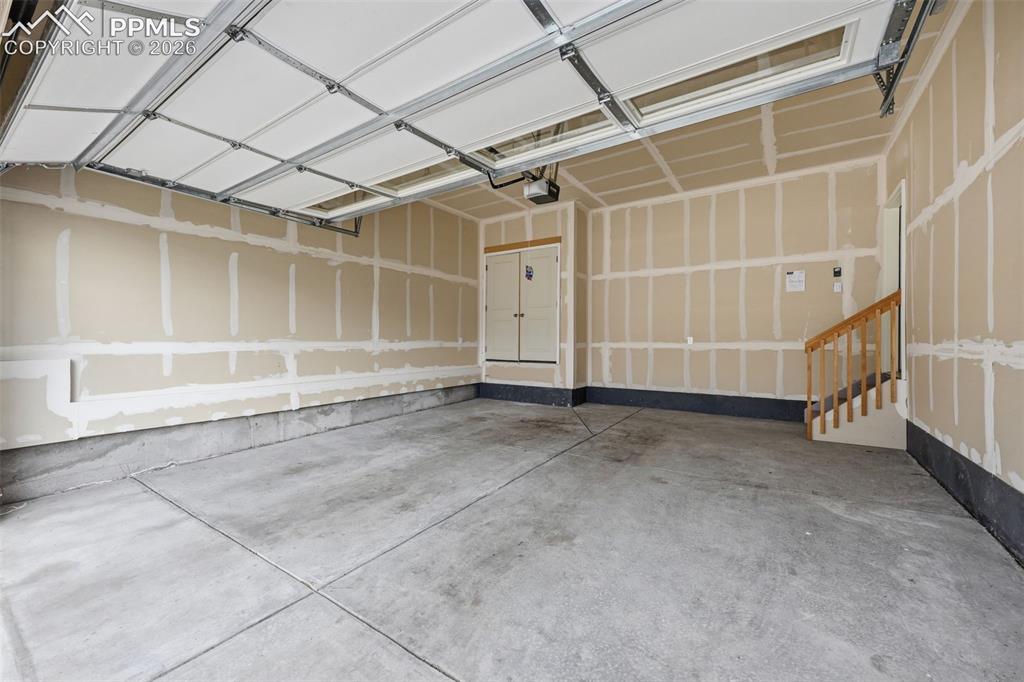 Image 19 of 23: Attached garage interior featuring a concrete floor, unpainted drywall, and