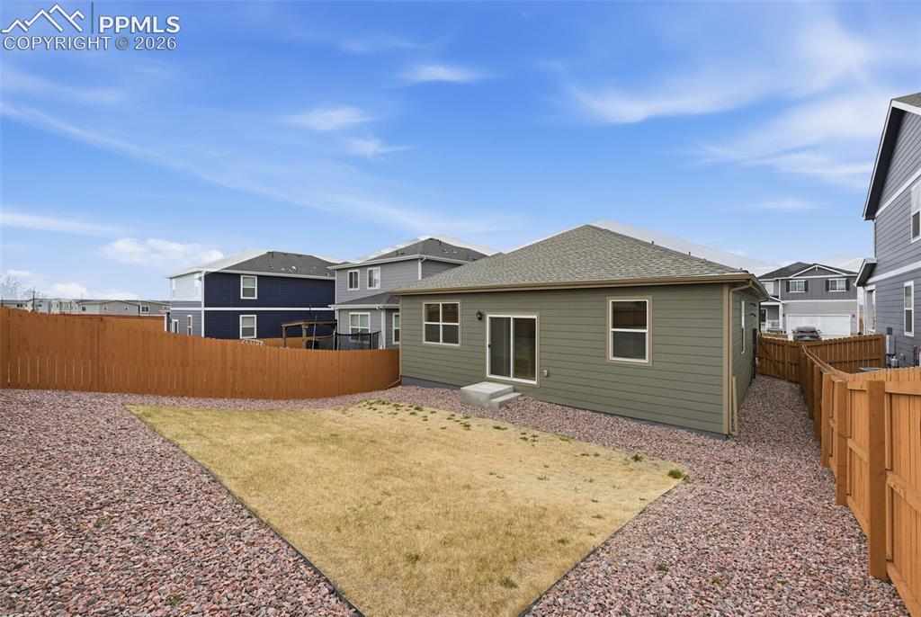 Image 21 of 23: Expansive backyard featuring a partial lawn area, gravel landscaping, and a