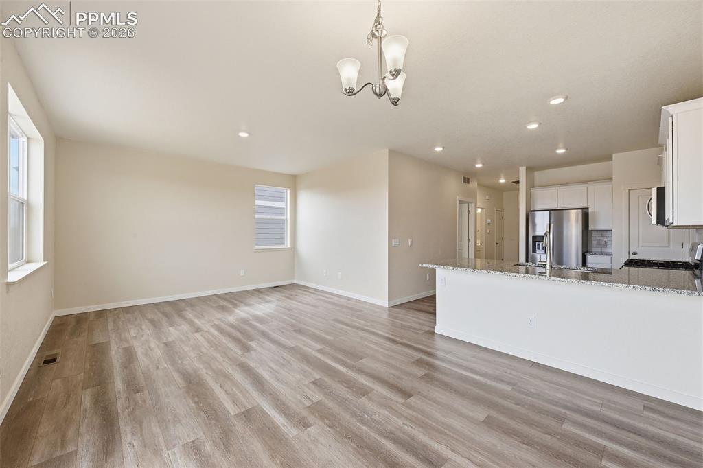 Image 4 of 23: Open concept living area featuring wood-finish flooring, recessed lighting,