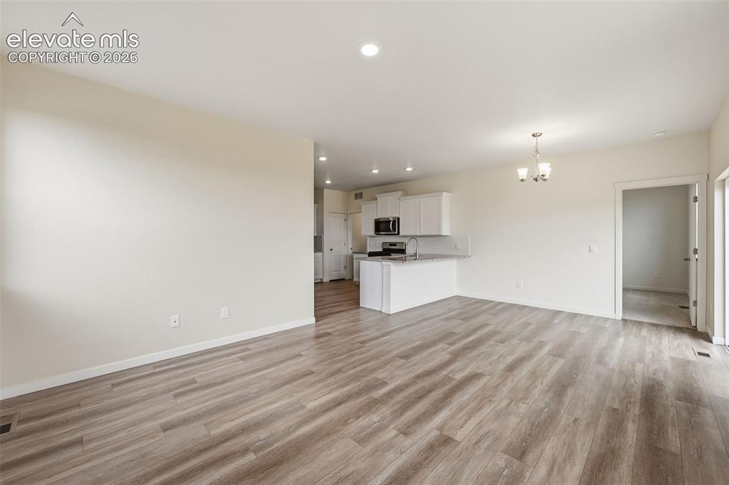 Image 7 of 23: Spacious living area featuring wood-finish flooring, recessed lighting, and