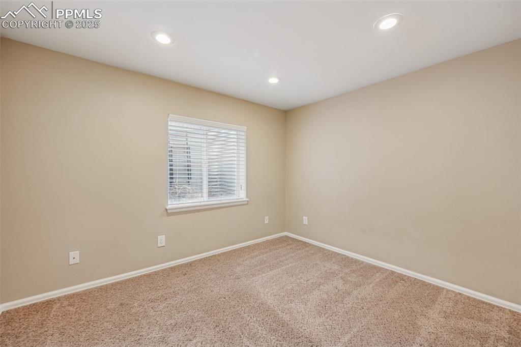 Image 28 of 39: Bright basement bedroom with neutral colors and recessed lighting