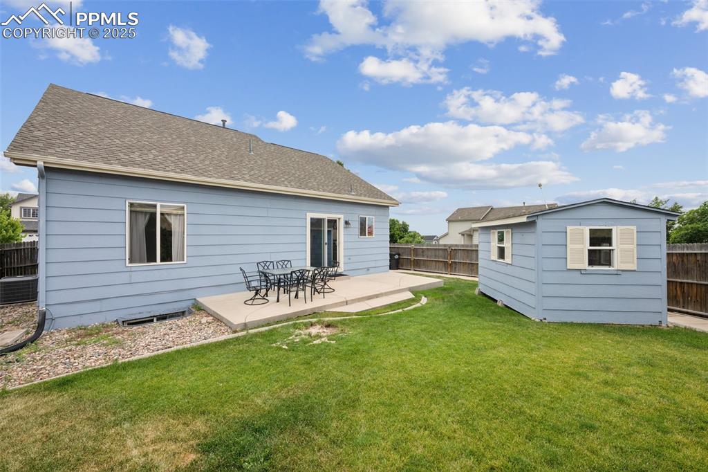 Image 35 of 39: Rear view of property with a fenced backyard, concrete patio and a storage 
