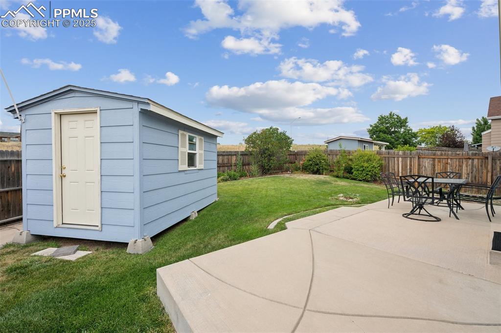 Image 41 of 43: Fenced backyard featuring a storage shed and large patio for entertaining