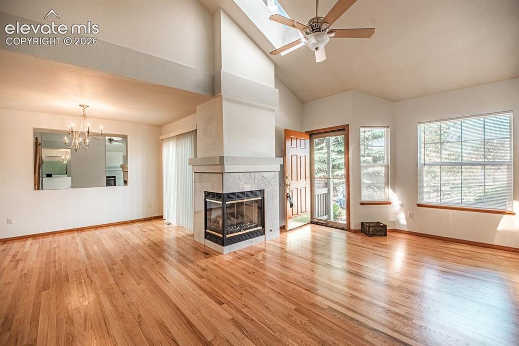 Image 12 of 38: Spacious living area featuring high vaulted ceilings, skylight, and a corne