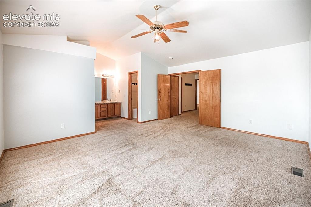 Image 16 of 38: Spacious carpeted room featuring a vaulted ceiling with a ceiling fan, ligh