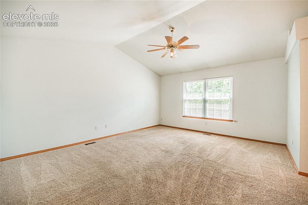Image 17 of 38: Spacious room featuring vaulted ceilings, neutral carpet, white walls, wood