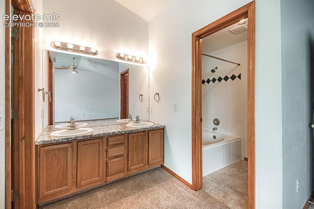 Image 23 of 38: Bathroom featuring a dual vanity with granite-patterned countertops, wood c