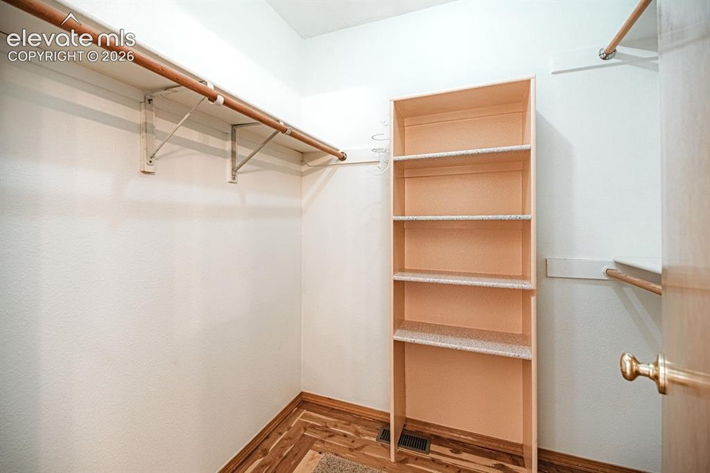 Image 25 of 38: Walk-in closet featuring wood-finish flooring, built-in shelving, and multi