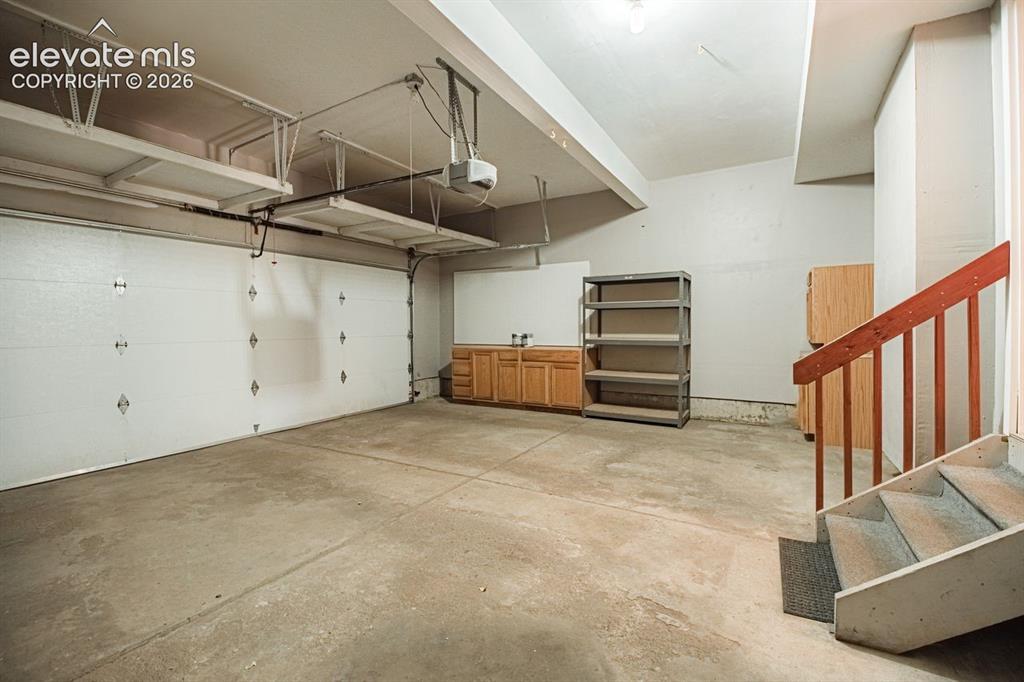 Image 33 of 38: Spacious garage with concrete flooring, two overhead garage doors, and buil
