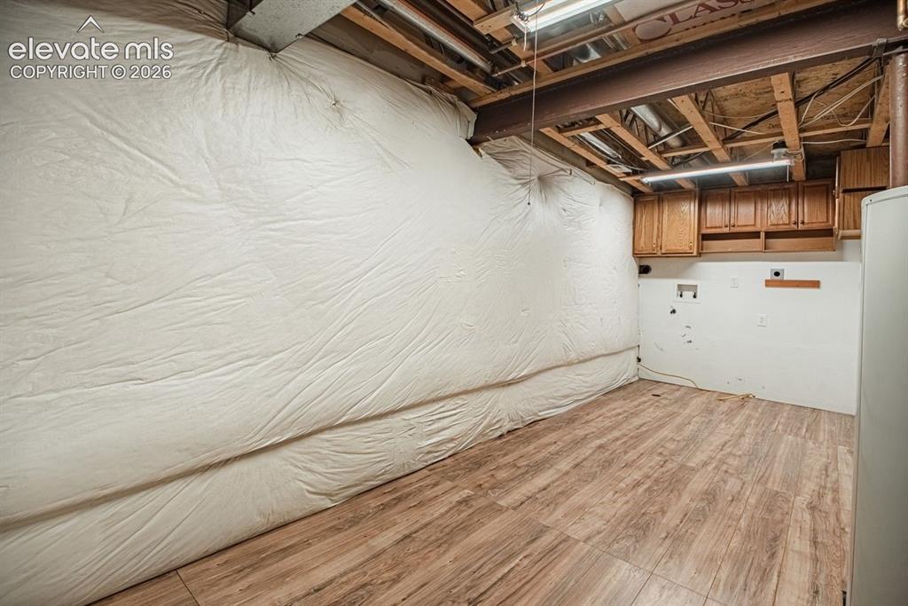 Image 35 of 38: Finished basement room featuring wood-finish flooring, exposed ceiling jois