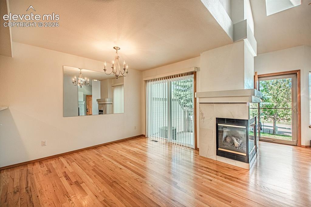 Image 6 of 38: Hardwood flooring extending throughout, complemented by a central chandelie