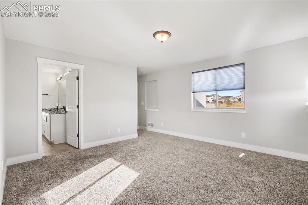 Image 14 of 20: Primary bedroom with warm color carpet and window coverings