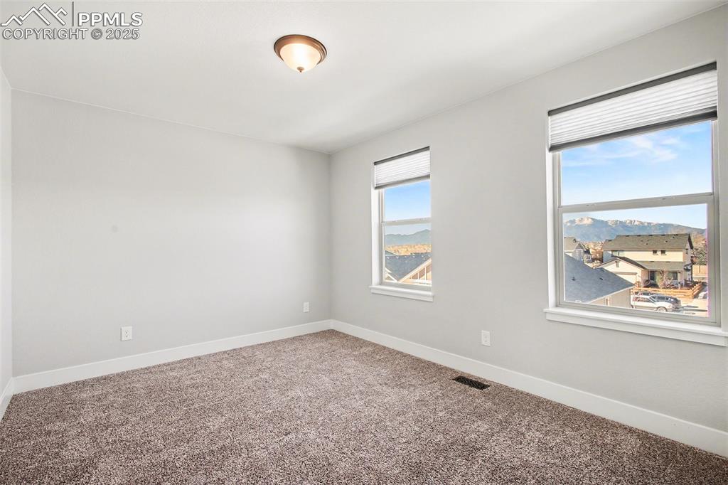 Image 18 of 20: Second sunny guest bedroom with beautiful carpet and mountain views