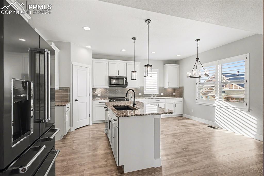 Image 8 of 20: An amazing kitchen with under counter lighting, granite, tiled backsplash a