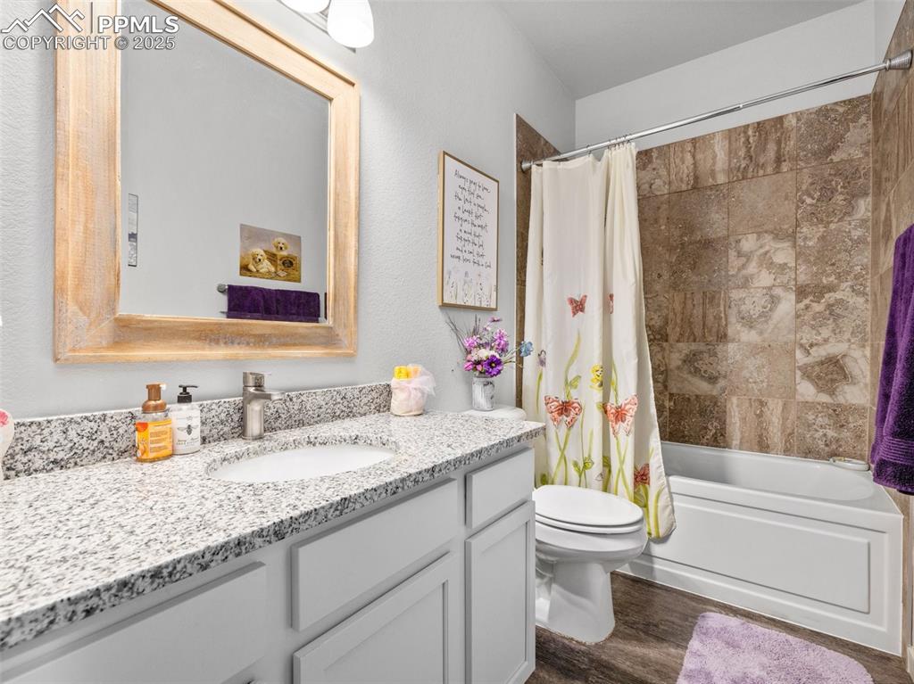 Image 18 of 25: Bathroom with vanity, shower / bath combination with curtain, and wood fini