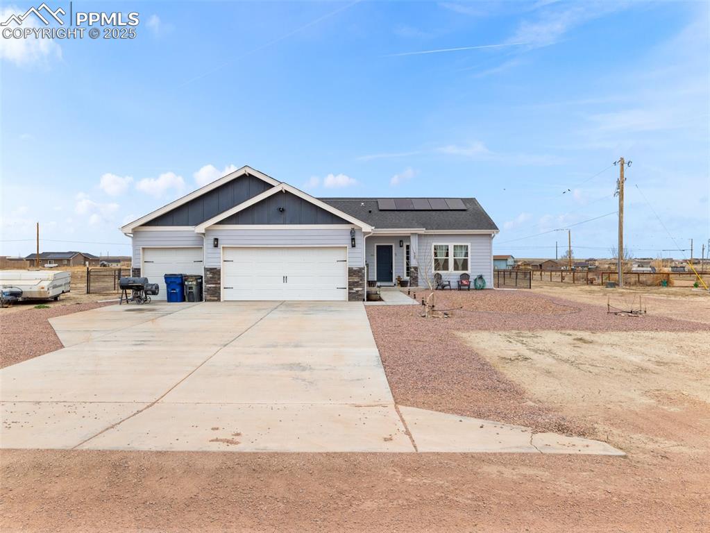 Image 20 of 25: View of front of home with a garage, solar panels, driveway, and board and