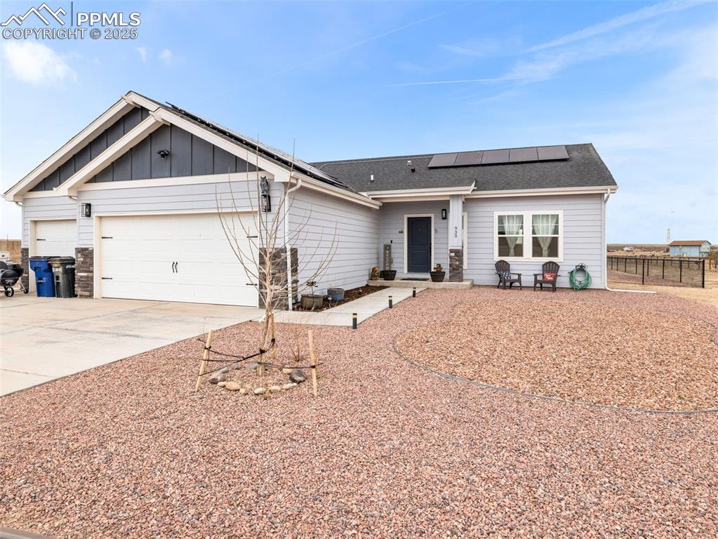 Image 25 of 25: Single story home with a garage, roof mounted solar panels, driveway, board