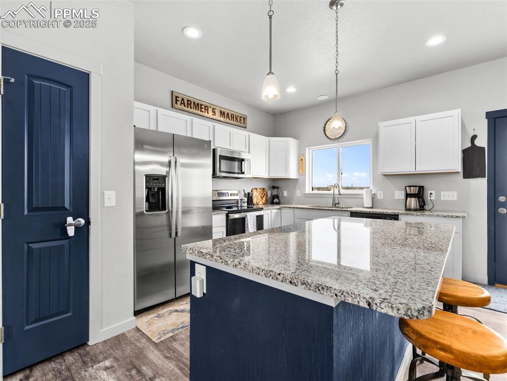 Image 6 of 25: Kitchen with stainless steel appliances, a breakfast bar area, dark wood-st