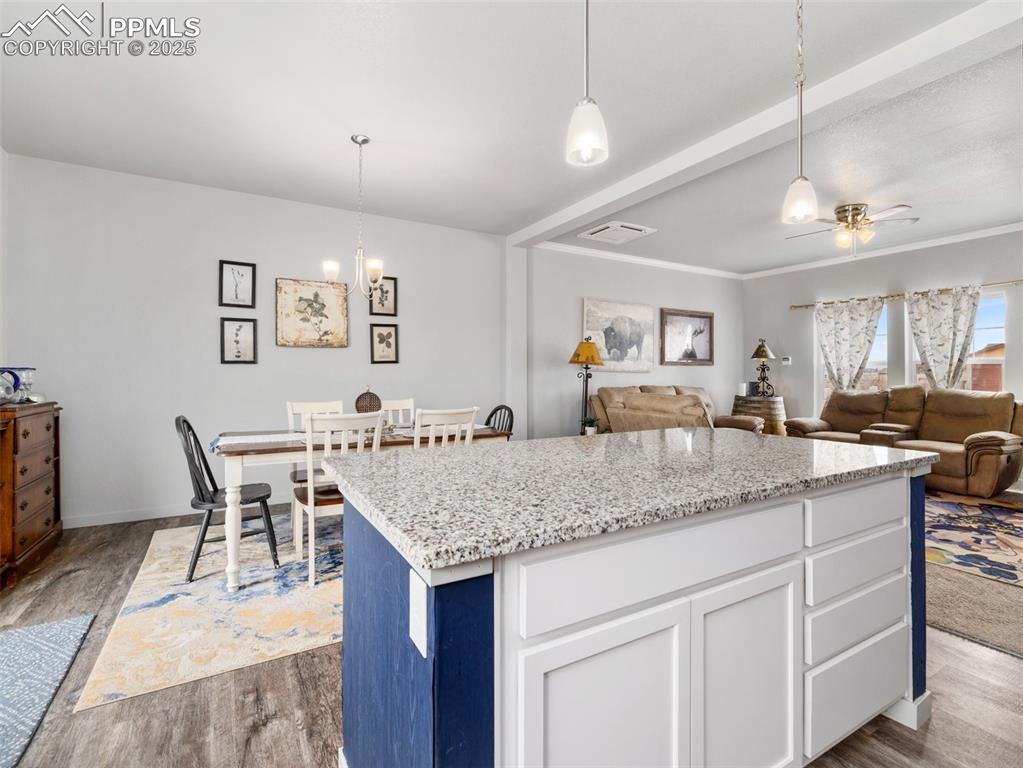 Image 8 of 25: Kitchen featuring wood finished floors, a center island, white cabinets, an