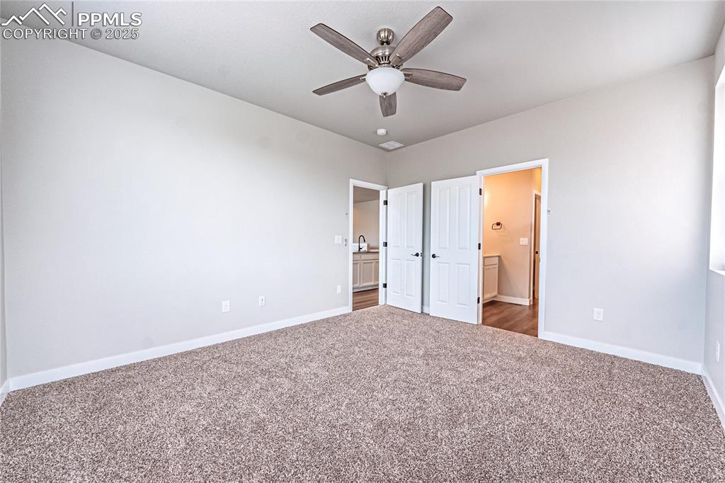Image 10 of 39: Unfurnished bedroom featuring carpet floors, ensuite bath, and a ceiling fa