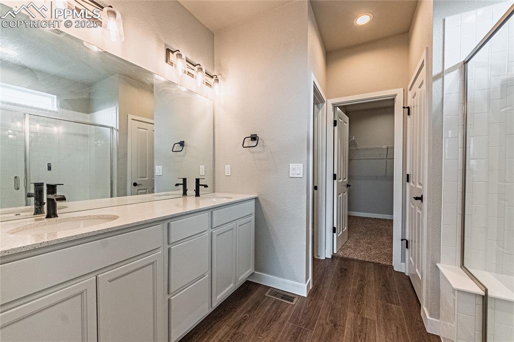Image 12 of 39: Full bathroom featuring a stall shower, wood finished floors, double vanity