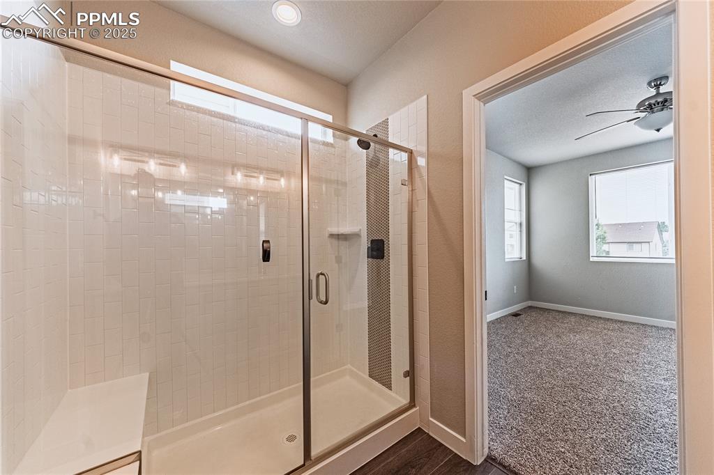 Image 13 of 39: Bathroom featuring a shower stall, a textured ceiling, ceiling fan, and woo