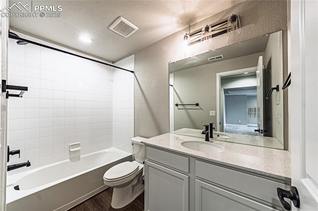Image 28 of 39: Full bath with a textured ceiling, vanity, shower / bathtub combination, a