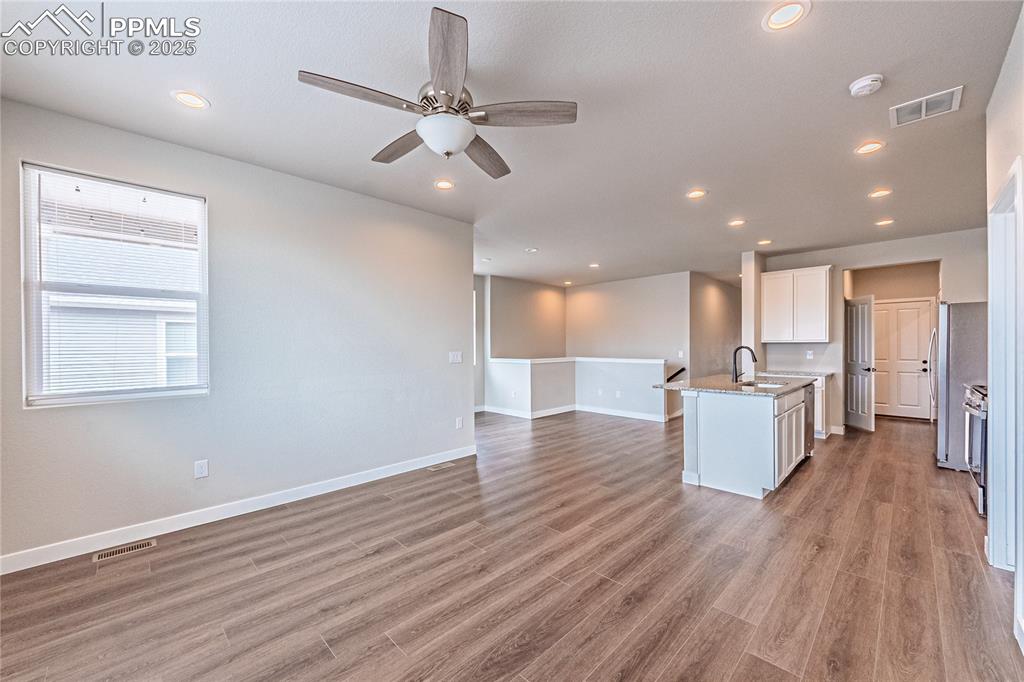 Image 3 of 39: Kitchen with open floor plan, white cabinets, a ceiling fan, light wood fin