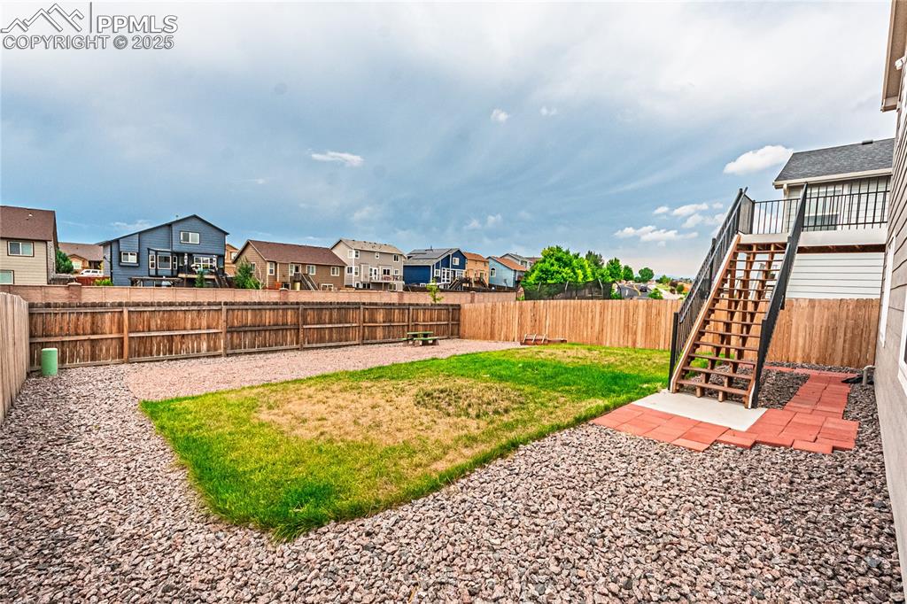 Image 33 of 39: Fenced backyard with a residential view and stairs