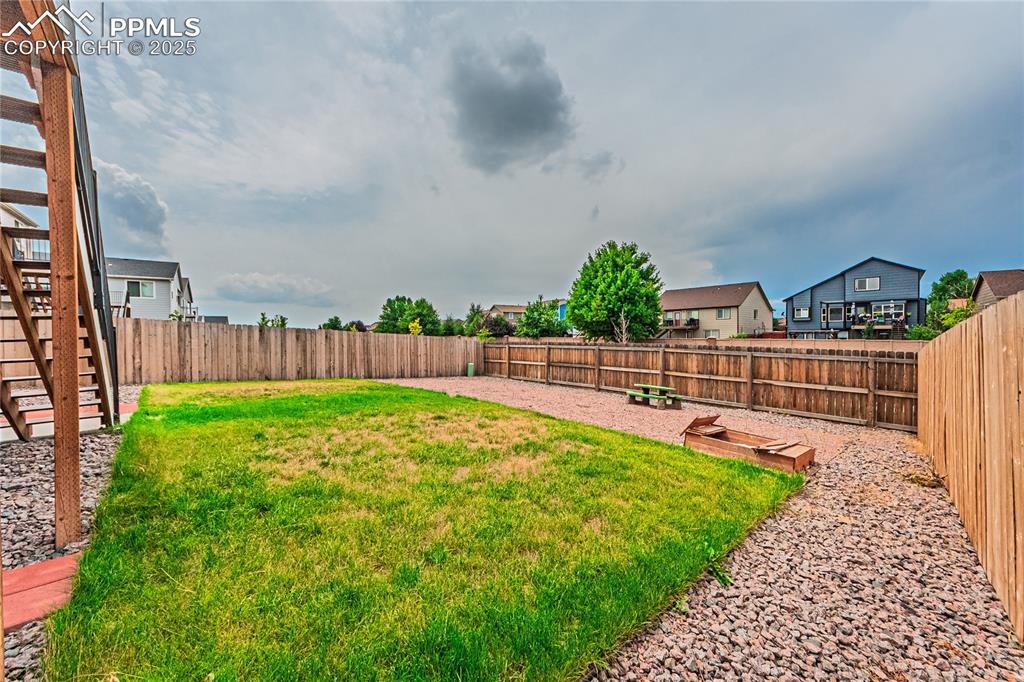 Image 34 of 39: Fenced backyard with stairway and a residential view